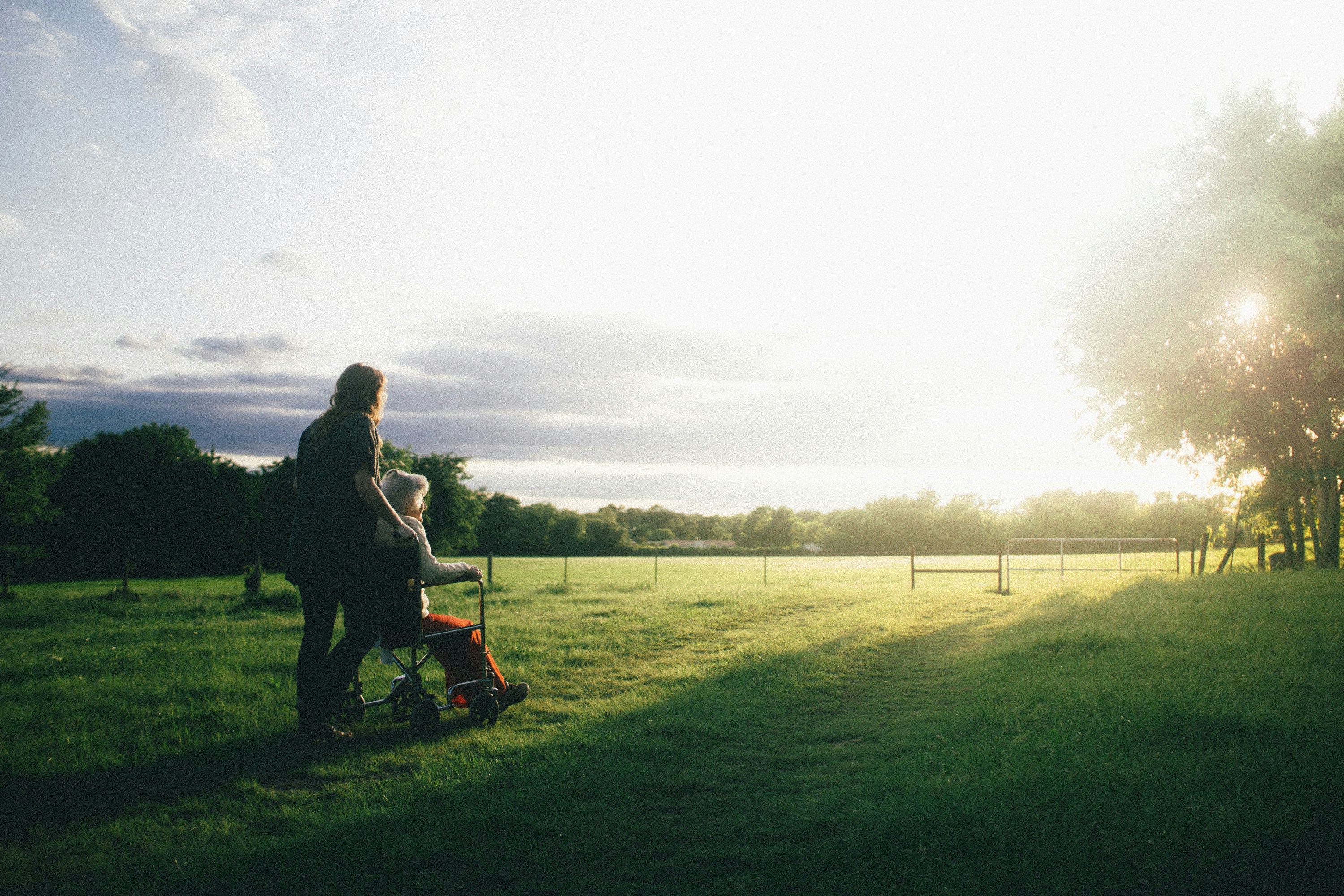 Pflegeperson mit Rollstuhl in der Natur